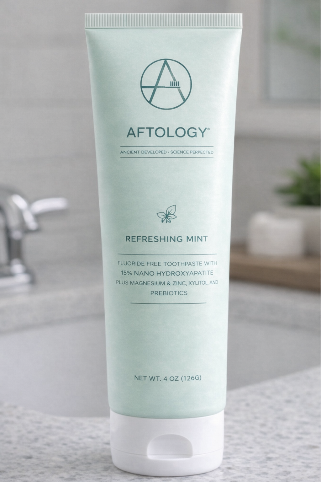 Aftology nano-hydroxyapatite toothpaste tube displayed beside bathroom sink in clean modern setting