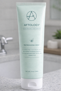 Aftology nano-hydroxyapatite toothpaste tube displayed beside bathroom sink in clean modern setting