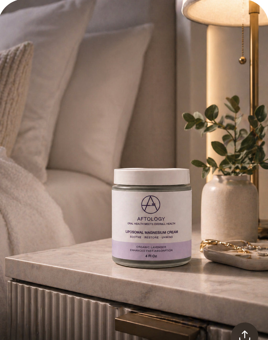 Jar of Aftology liposomal magnesium glycinate cream on a nightstand with a cozy room setting.