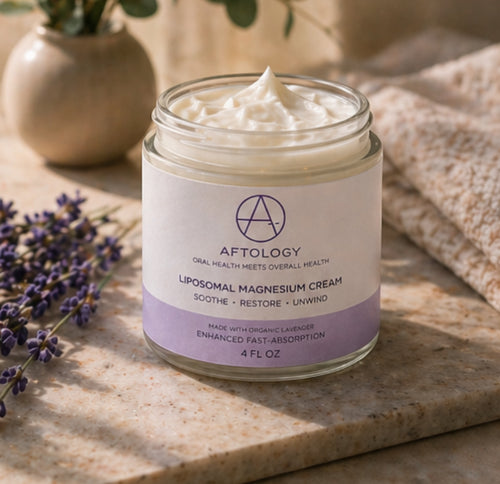Jar of Aftology liposomal magnesium glycinate cream on a marble surface with lavender flowers and a plant in the background
